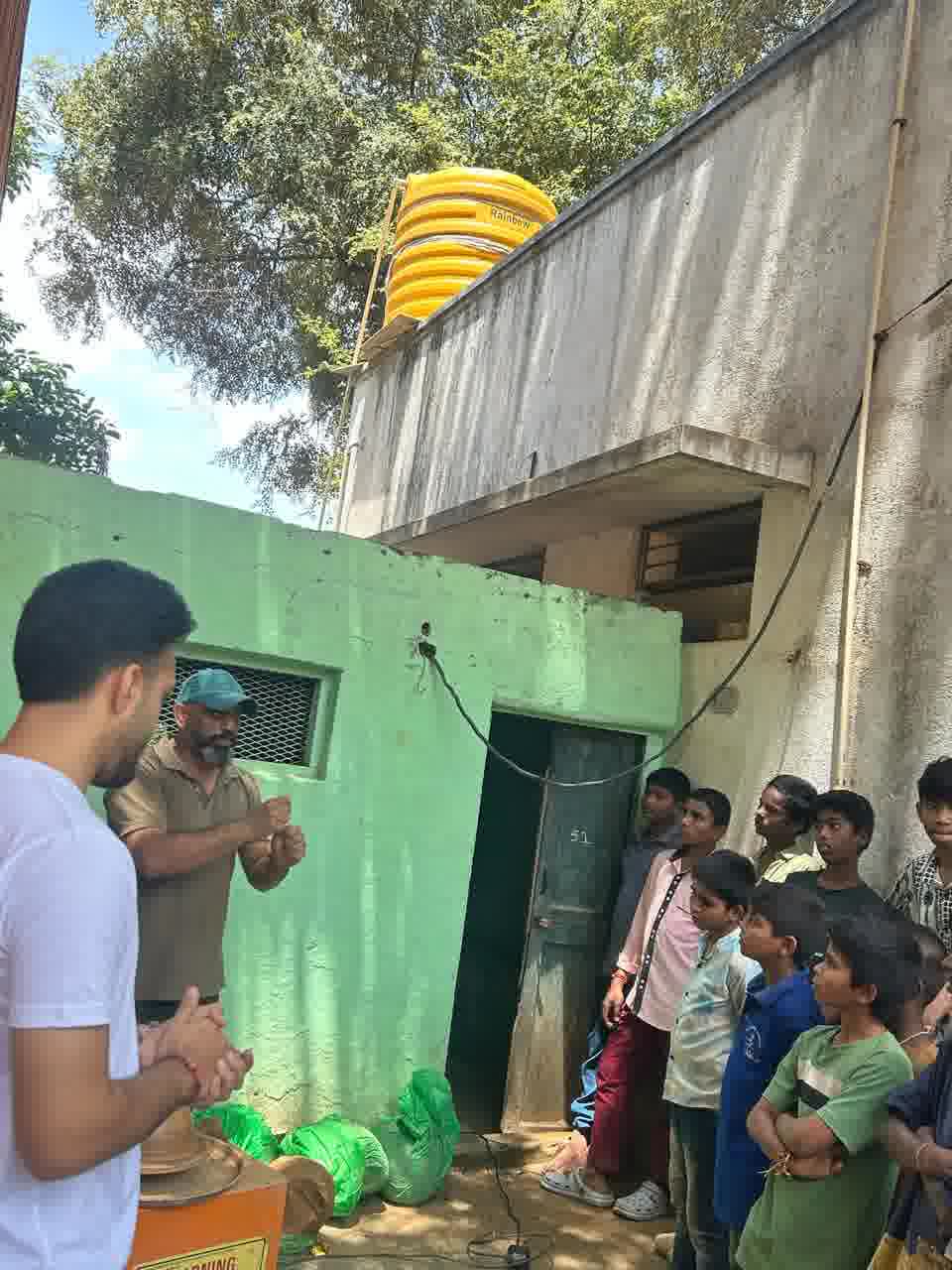 A potter demonstrating at the wheel outdoors while a group of boys watch from against the wall
