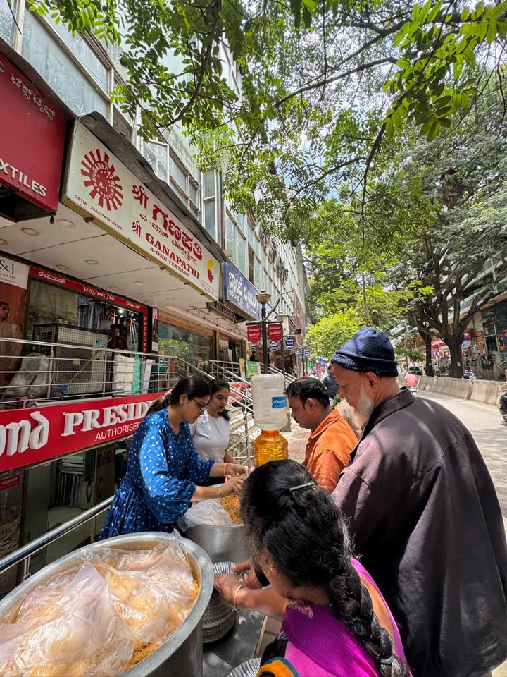 Volunteers serving rice from large vessels to people waiting on the BVK Iyengar Road footpath