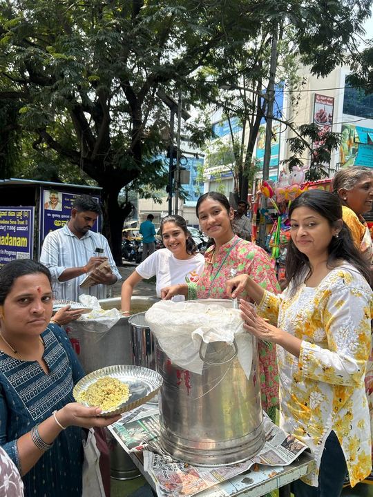 The serving team smiling behind the vessels, one holding up a plate of food
